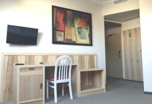 a desk with a chair and a television on a wall at Pension Weber in Vienna