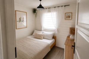 a small bedroom with a bed and a window at Domek LENA in Giżycko
