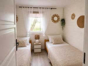 two beds in a small room with a window at Domek LENA in Giżycko