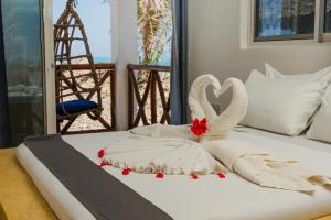 a bed with two swans made out of towels at Aquelia Rose Hotel in Jambiani