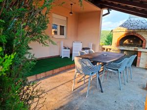 a table and chairs on a patio with a fireplace at Vikendica Vlahić, Goranci in Mostar