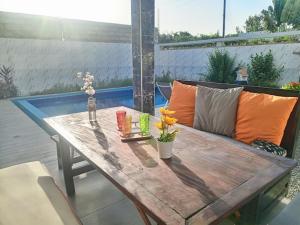 a wooden table with flowers and a couch on a patio at Villa Bamba TERANGA in Somone