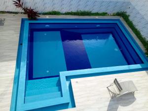 a blue swimming pool with a chair next to it at Villa Bamba TERANGA in Somone