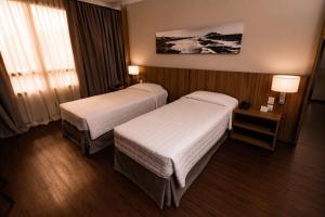 a hotel room with two beds and a window at Kennedy Executive Hotel in São José +104 photos