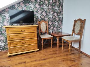 a tv on a dresser with two chairs and a table at Gloria in Olomouc