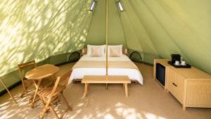 a bedroom in a green tent with a bed and a table at La Ballenera Lodge in Guaquen