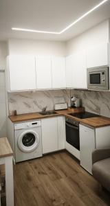 a kitchen with a washing machine and a microwave at Pensión Vázquez in Vimianzo