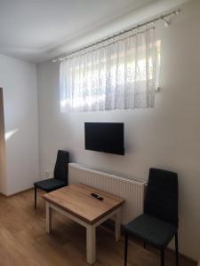 a living room with a table and two chairs and a tv at Gloria in Olomouc