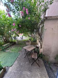 a garden with a bench and a tree with pink flowers at Le Bourguignon - Proche centre ville et Tram in Dijon