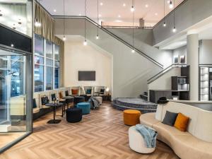 a living room with a couch and tables and chairs at ibis Styles Bielefeld City in Bielefeld