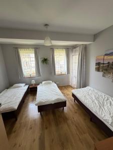 two beds in a room with wooden floors and windows at Apartament pod Dębami in Rowy