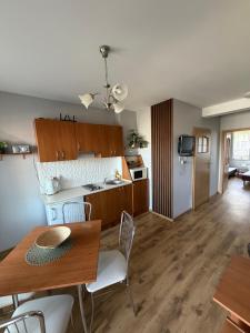 a kitchen and living room with a table and chairs at Apartament pod Dębami in Rowy
