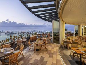 ein Restaurant mit Tischen und Stühlen auf einem Balkon in der Unterkunft Rixos Gulf Hotel Doha in Doha