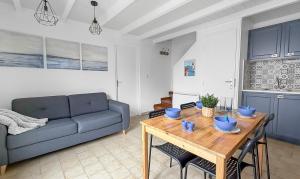 a living room with a blue couch and a wooden table at Petit cocon, parking et piscine à Marseillan in Marseillan
