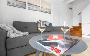 a living room with a couch and two glasses of wine at Petit cocon, parking et piscine à Marseillan in Marseillan