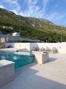 a house with a swimming pool and a mountain at Apartments M&E in Mokošica
