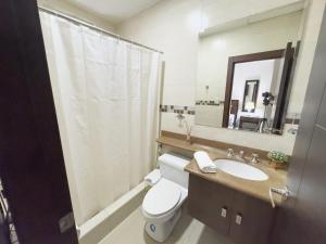a bathroom with a toilet and a sink and a mirror at Amazing apartment near US Consulate in Guayaquil
