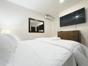 a bedroom with two white beds and a flat screen tv at Amazing apartment near US Consulate in Guayaquil
