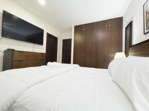 a bedroom with two white beds and a flat screen tv at Amazing apartment near US Consulate in Guayaquil