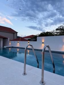 a swimming pool with two metal rails next to a building at Apartments M&E in Mokošica