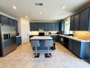a kitchen with blue cabinets and a large island with bar stools at Spacious Private Bedrooms With Full Amenities Near Grocery Stores & Main Highway Routes in Fontana
