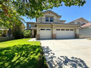 a house with two garage doors in a yard at Spacious Private Bedrooms With Full Amenities Near Grocery Stores & Main Highway Routes in Fontana