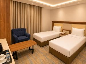 a hotel room with two beds and a blue chair at شركة نيلوفر بلس للخدمات الفندقيه in Abha