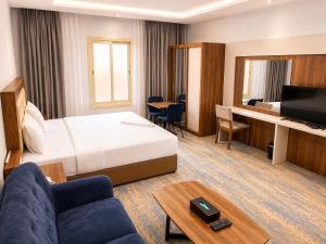 a hotel room with a bed and a couch and a desk at شركة نيلوفر بلس للخدمات الفندقيه in Abha