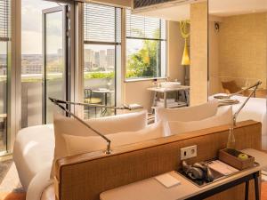 a living room with white furniture and a large window at Too Hotel & Spa Paris - MGallery Collection in Paris