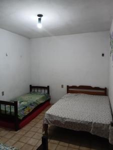 two beds in a room with white walls at Pousada Santa face Rua do Cruzeiro 395 endereço in Juazeiro do Norte