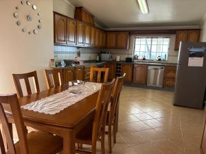 a kitchen with a table with chairs and a refrigerator at Retiro da Ribeira in Angra do Heroísmo