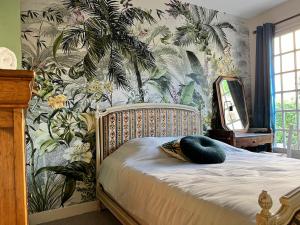 een slaapkamer met een bed met tropisch behang bij House with garden in Pérouges