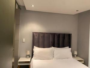 a bed with a black headboard and white pillows at Windhoek perfect stay in Windhoek