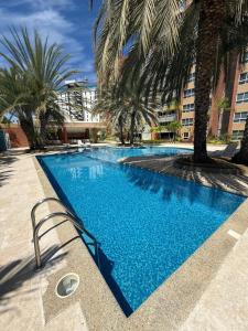 a large blue swimming pool with palm trees and buildings at Apartamento en Pampatar in Pampatar