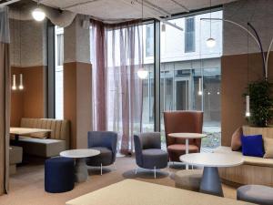 a lobby with tables and chairs and windows at Adagio Access Gent Centrum Dampoort in Ghent