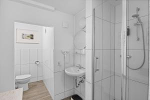 a white bathroom with a toilet and a sink at Gästehaus Parkblick in Rust +98 photos
