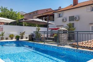 a swimming pool in front of a house with an umbrella at Apartments Baretić in Crikvenica