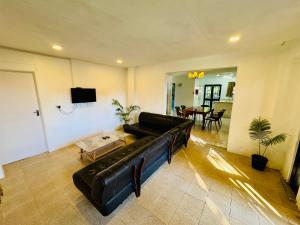 a large living room with a black leather couch at Three bedroom apartment in Suva
