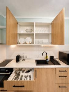 a kitchen with a sink and a stove top oven at Odyssey Mare Steps from the Sea in Perea +6 photos