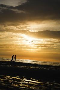 two people walking on the beach at sunset at B&Beach Zandvoort in Zandvoort