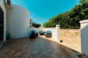 a patio with blue chairs and a wall at Arabic Sea Apartments in Porto Cesareo