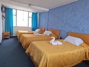 two swans are sitting on two beds in a room at Hotel Calima in Quito