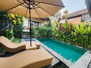a pool with chairs and an umbrella next to a house at pondok ubud nia cahya in Tegalalang
