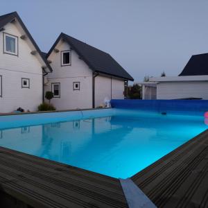 a large swimming pool in front of a house at Domki Perłowe in Dąbki