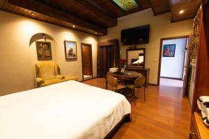 a hotel room with a bed and a table and a television at Hotel & Suites El Quijote in Cuenca