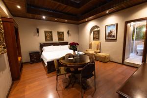 a bedroom with a bed and a table and a room with a bed at Hotel & Suites El Quijote in Cuenca