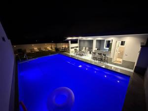 a blue swimming pool at night in front of a house at Villa Mešić in Stojčevac