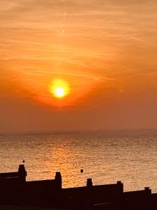 a sunset over the ocean with the sun at The Dairy stylish chalet for 2 opp the beach 1 minute walk in Whitstable