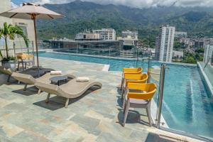 a pool on top of a building with chairs and an umbrella at Sonesta Hotel Ibagué in Ibagué