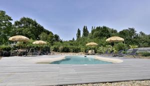 a small swimming pool with chairs and umbrellas at Le Nid de Mazerolles in Sucé